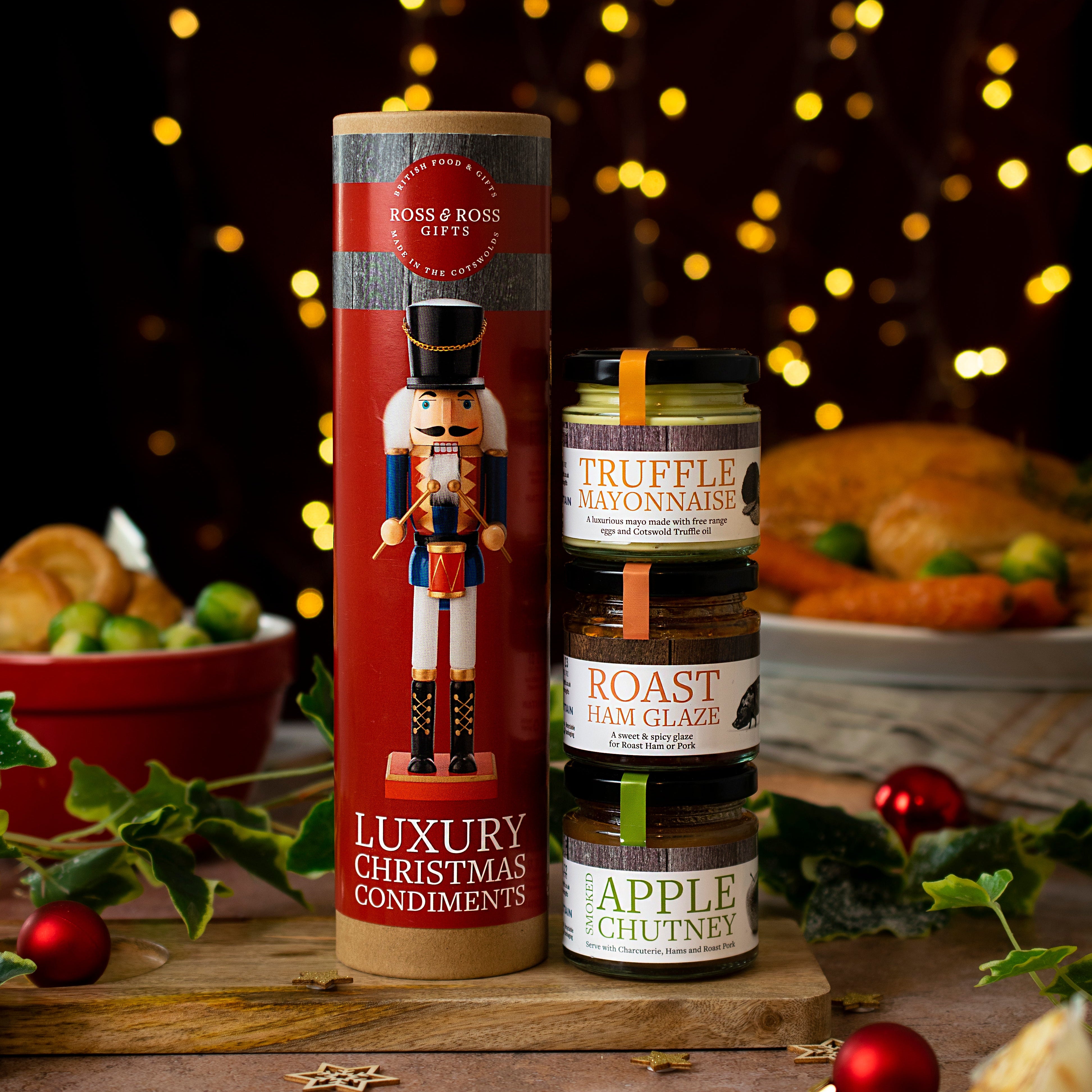 Two bottles of food products with decorative labels on a festive background with lights and food items.